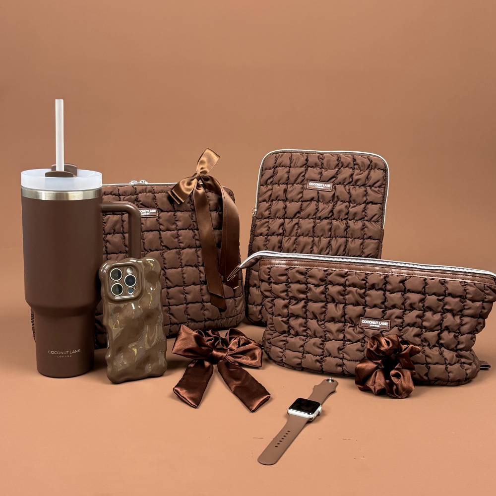 A laptop, phone case, and small pouch, all covered in pink fluffy material, rest on a brown cushion.