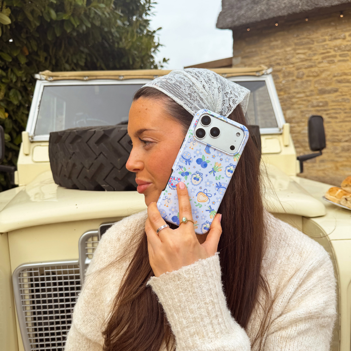 Girl holding blueberry picnic phone case to ear 