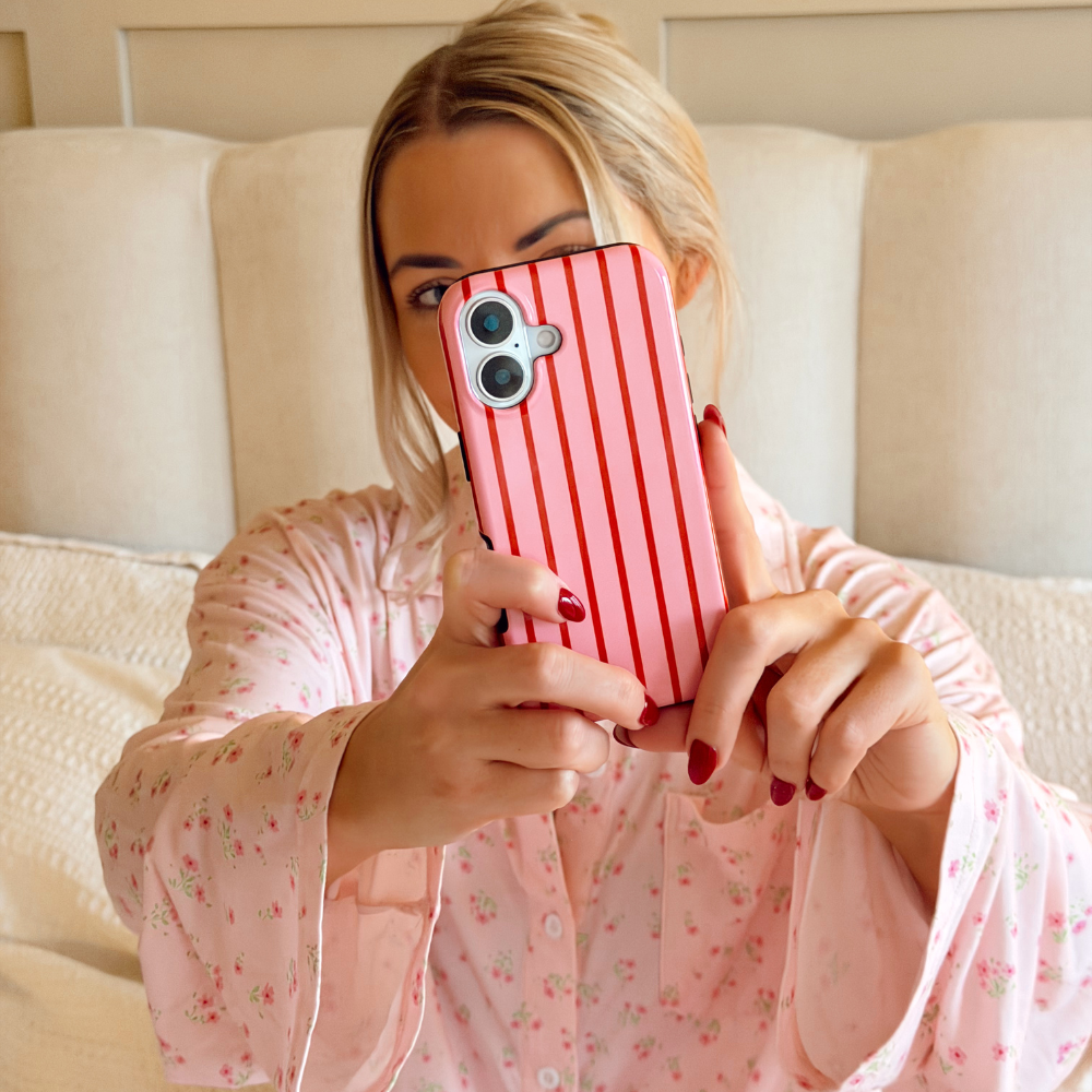 Girl taking selfie in cosy setting holding Cherry Stripes Tough Phone Case