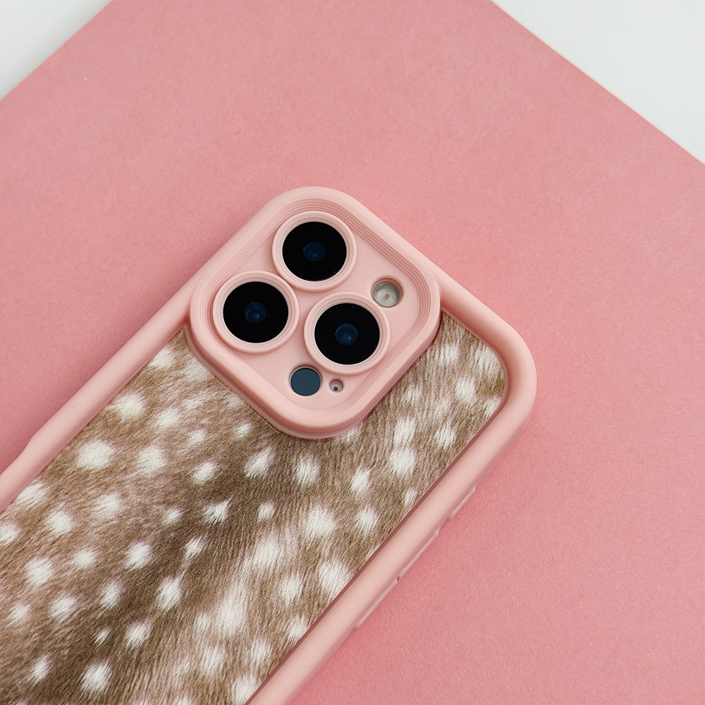 A phone case with pink edging and brown fawn-print center featuring white spots, shown on a phone against a solid pink background.