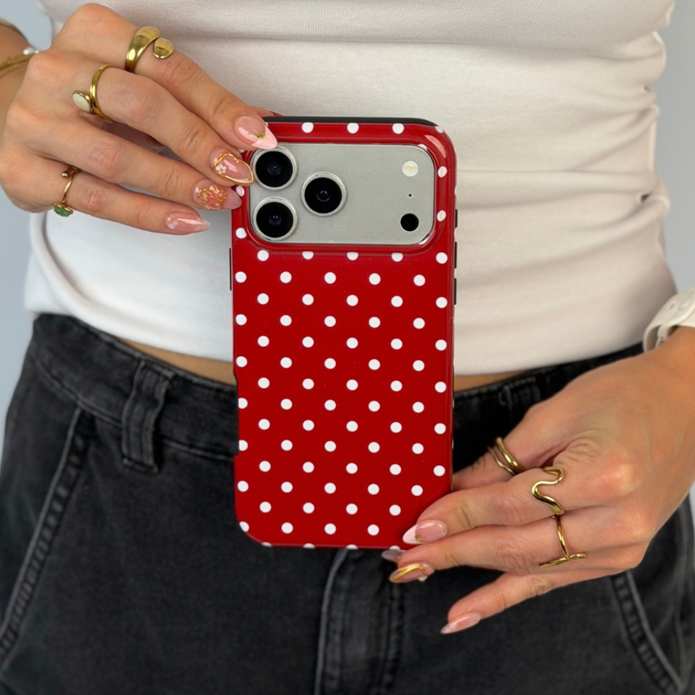 Woman holding an iphone, with a red and white polka dot phone case. 