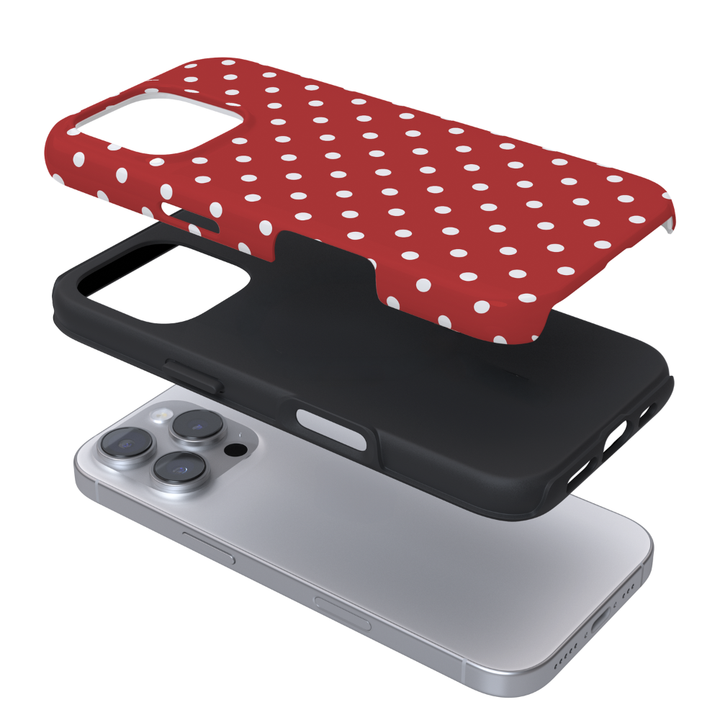A three-layer exploded view of a phone case set: a red case with white polka dots on top, a black protective layer in the middle, and a silver smartphone underneath on a white background.