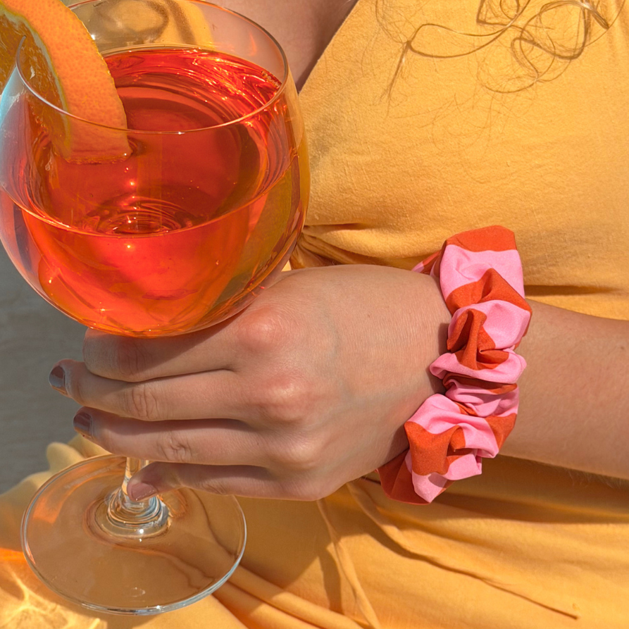Soleil Stripe Scrunchie on wrist holding aperol spritz