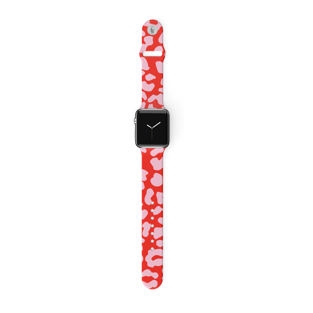 A smartwatch featuring a rectangular black screen and the Coconut Lane Red & Pink Leopard Apple Watch Strap, which showcases an abstract pattern. The silicone strap is displayed vertically, with the band open and extended upward and downward.