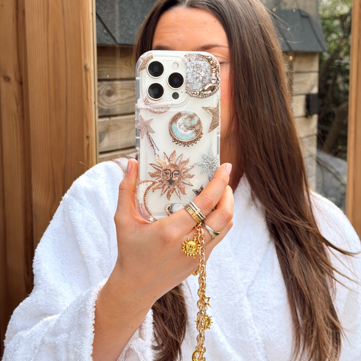Girl in sauna wearing white dressing gown holding her pastel celestial phone case