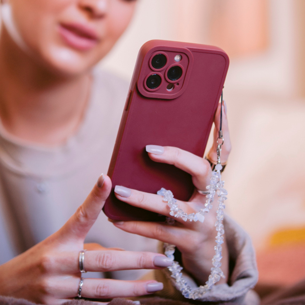 Pink phone with Coconut Lane Crystal Phone Strap - Moonstone, held in a hand with painted nails and rings.
