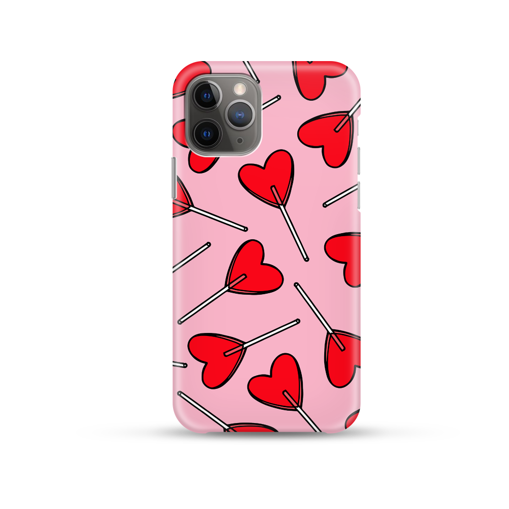 A Candy Hearts Phone Case by Coconut Lane, featuring a pink, soft flexible plastic design adorned with a pattern of sugary and sweet red heart-shaped lollipops, is displayed against a white background. The camera lenses are visible on the upper left corner of the phone.
